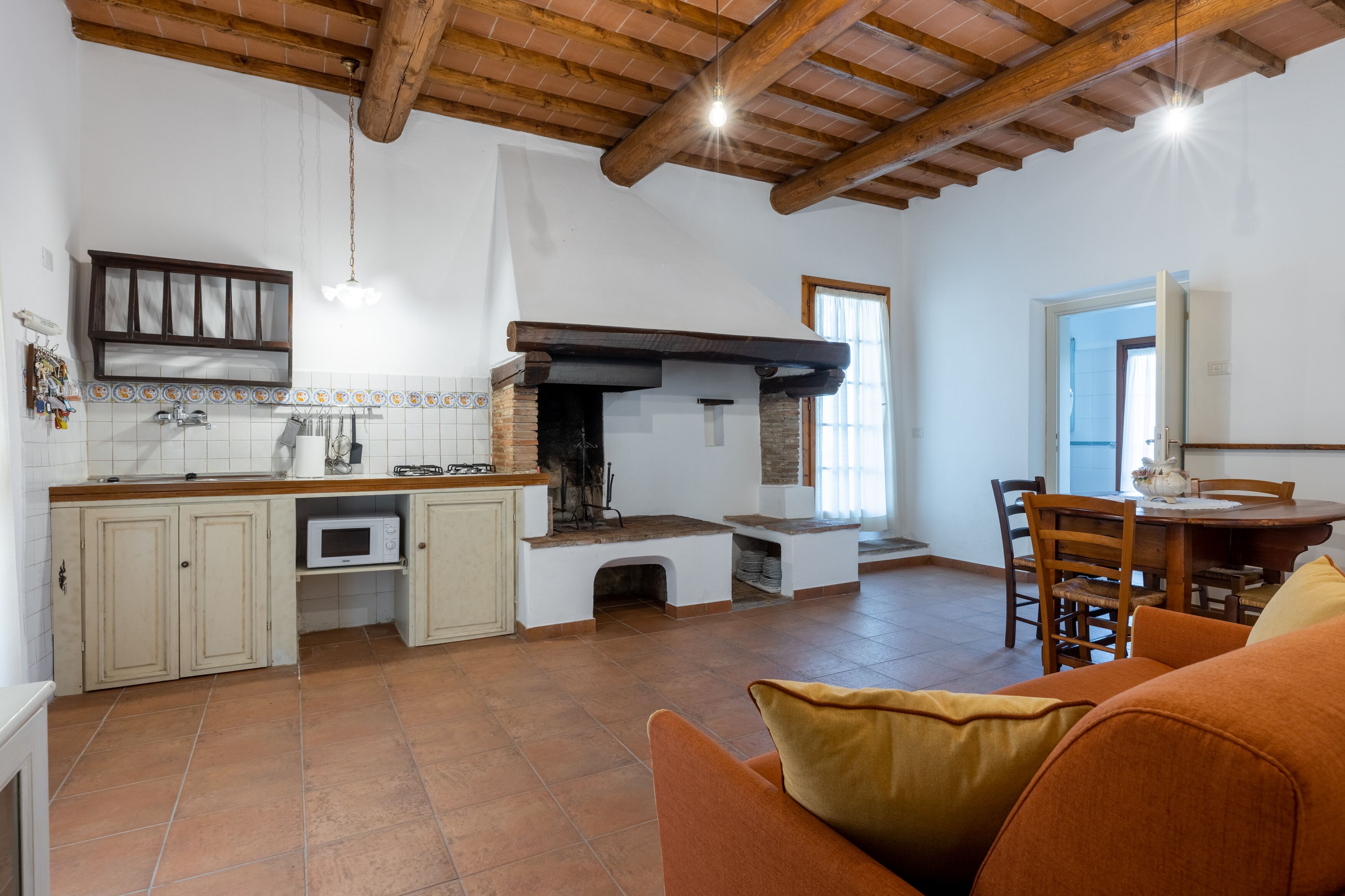 A spacious kitchen with a built-in oven, a dining area with a wooden table and chairs, and a cozy living space with a sofa.