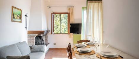 A dining area with a table set for four, a sofa, a fireplace, and a TV.