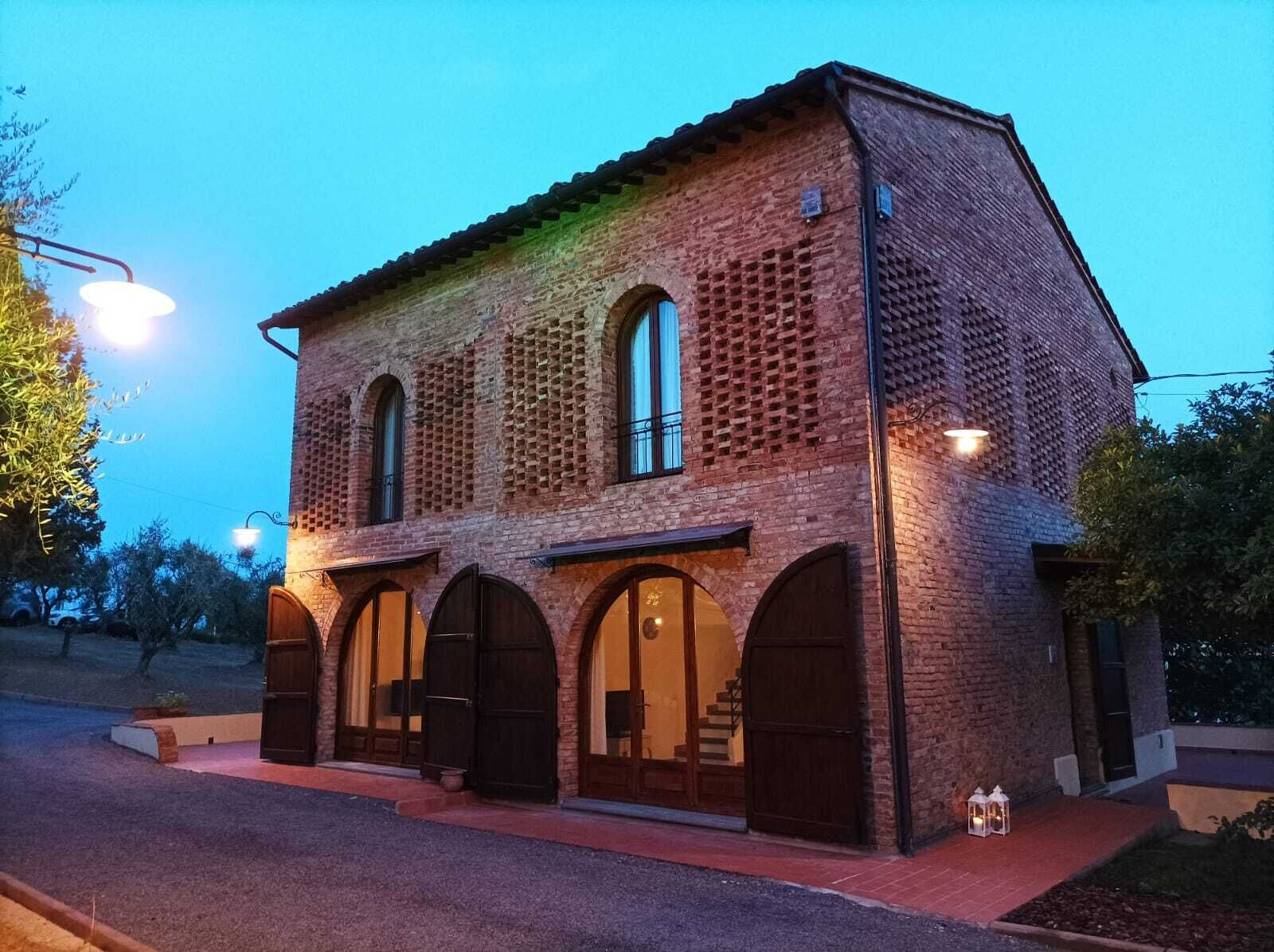 Um edifício de tijolos com janelas e portas em arco, teto plano e área de entrada pavimentada.