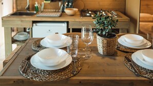 Una mesa de comedor de madera dispuesta con platos, vasos y una planta en maceta.