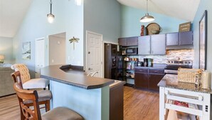 A modern kitchen with a central island, dark cabinets, and stainless steel appliances. - Margaritaville house next to pool (Osage Beach)