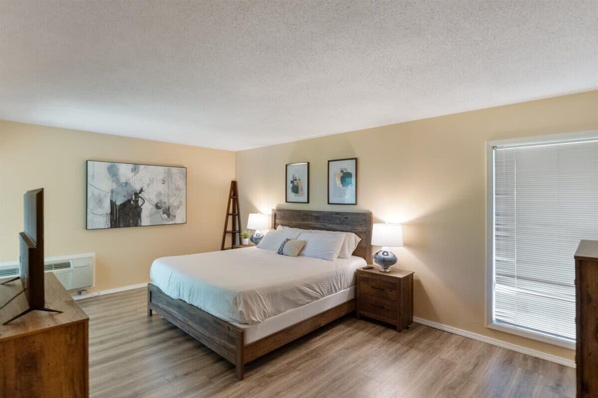 Une chambre à coucher avec un lit en bois, deux lampes de chevet, une échelle et des œuvres d’art accrochées aux murs.
