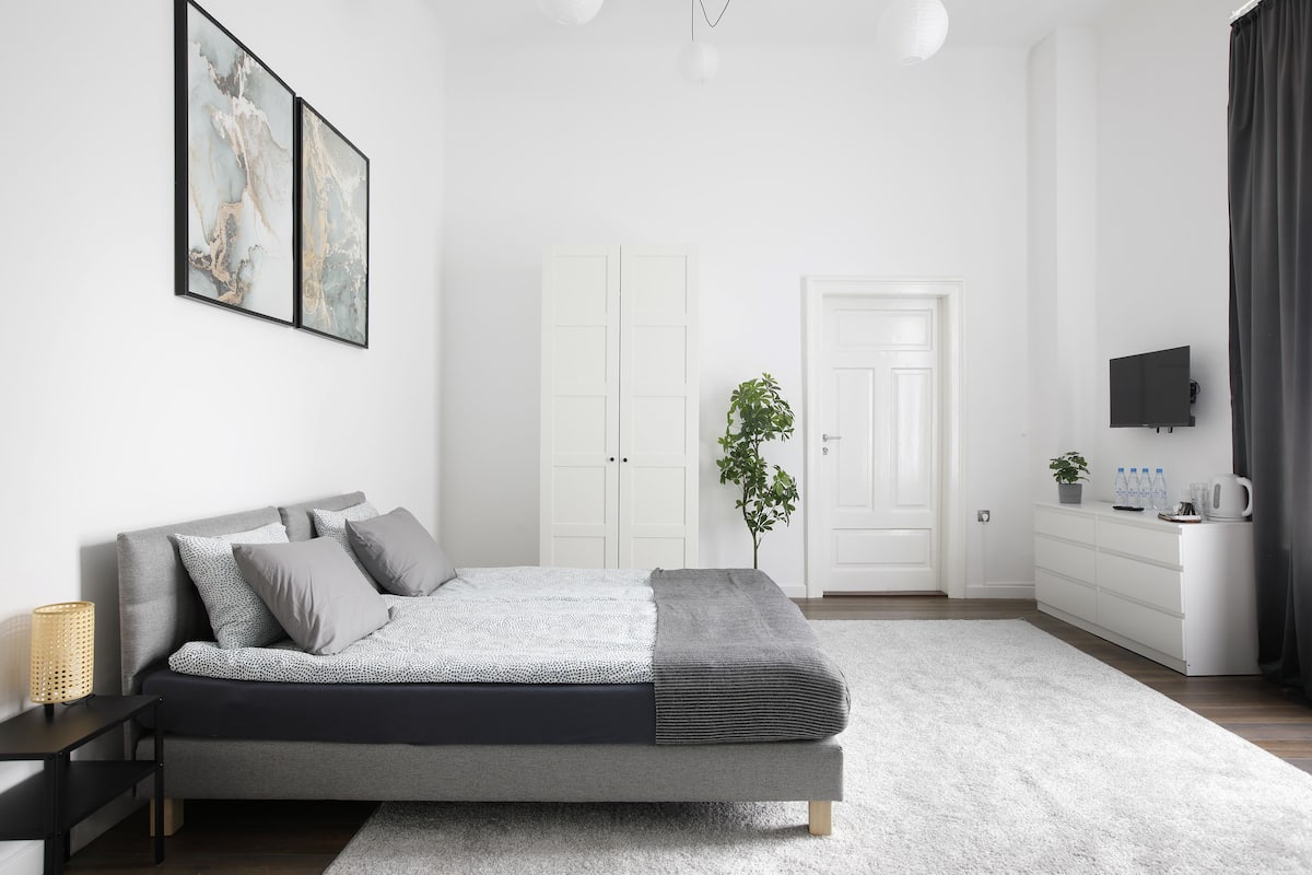 Ein modernes Schlafzimmer mit Bett, Nachttisch und Fernseher auf einer Kommode.