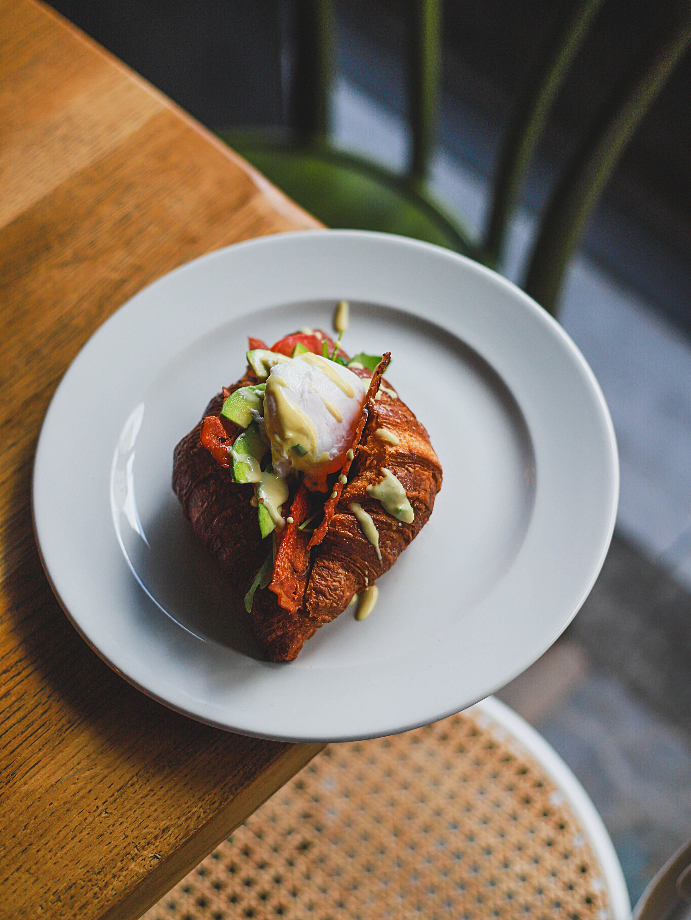 A plate of food with a poached egg, avocado, and greens on a white plate.