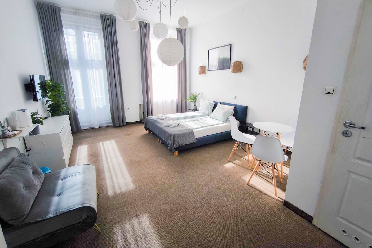 Ein modernes Schlafzimmer mit Bett, Nachttisch, Sessel und Schreibtisch mit Stuhl.