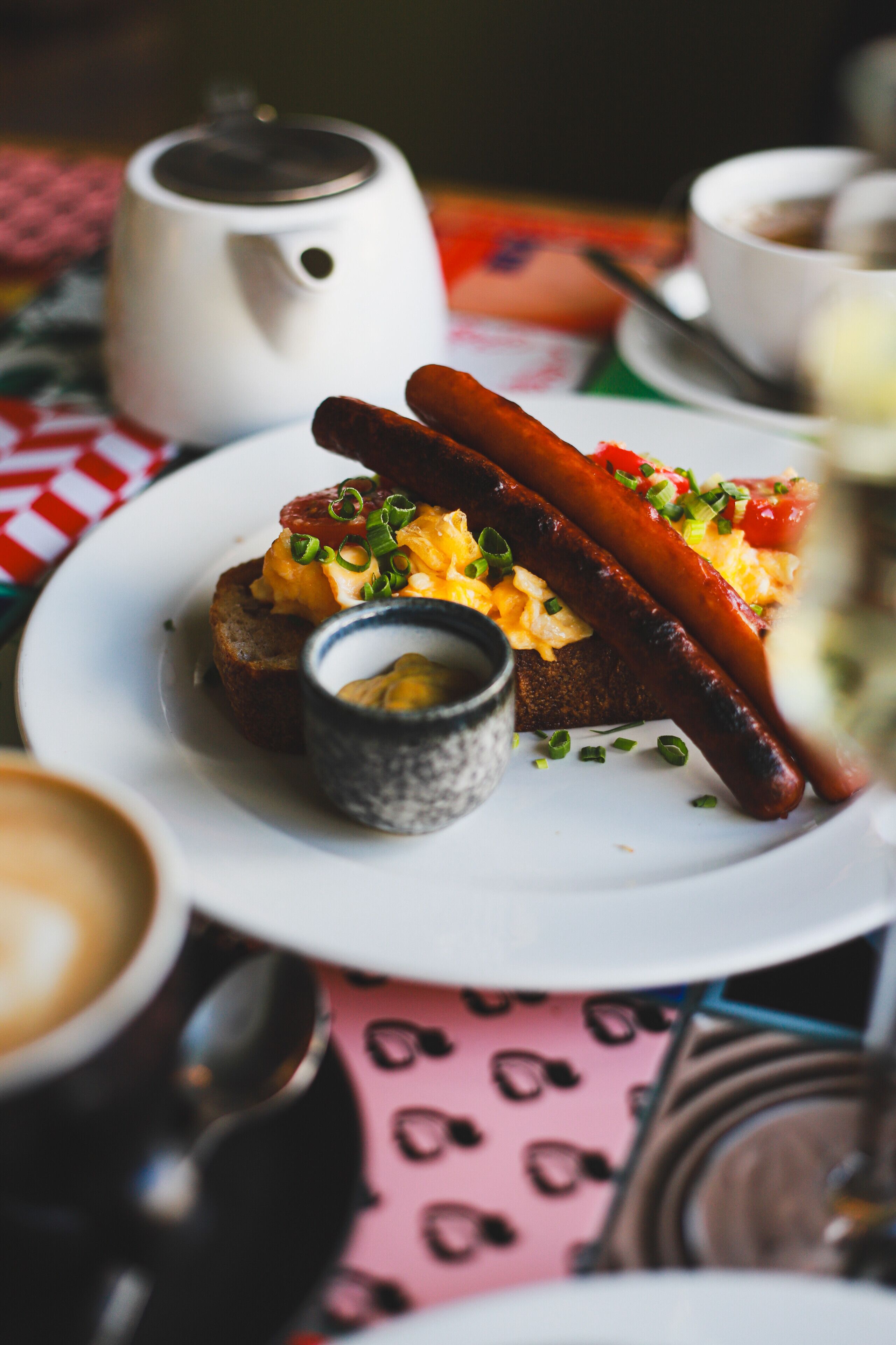 A breakfast plate with sausages, scrambled eggs, and a small cup of butter.