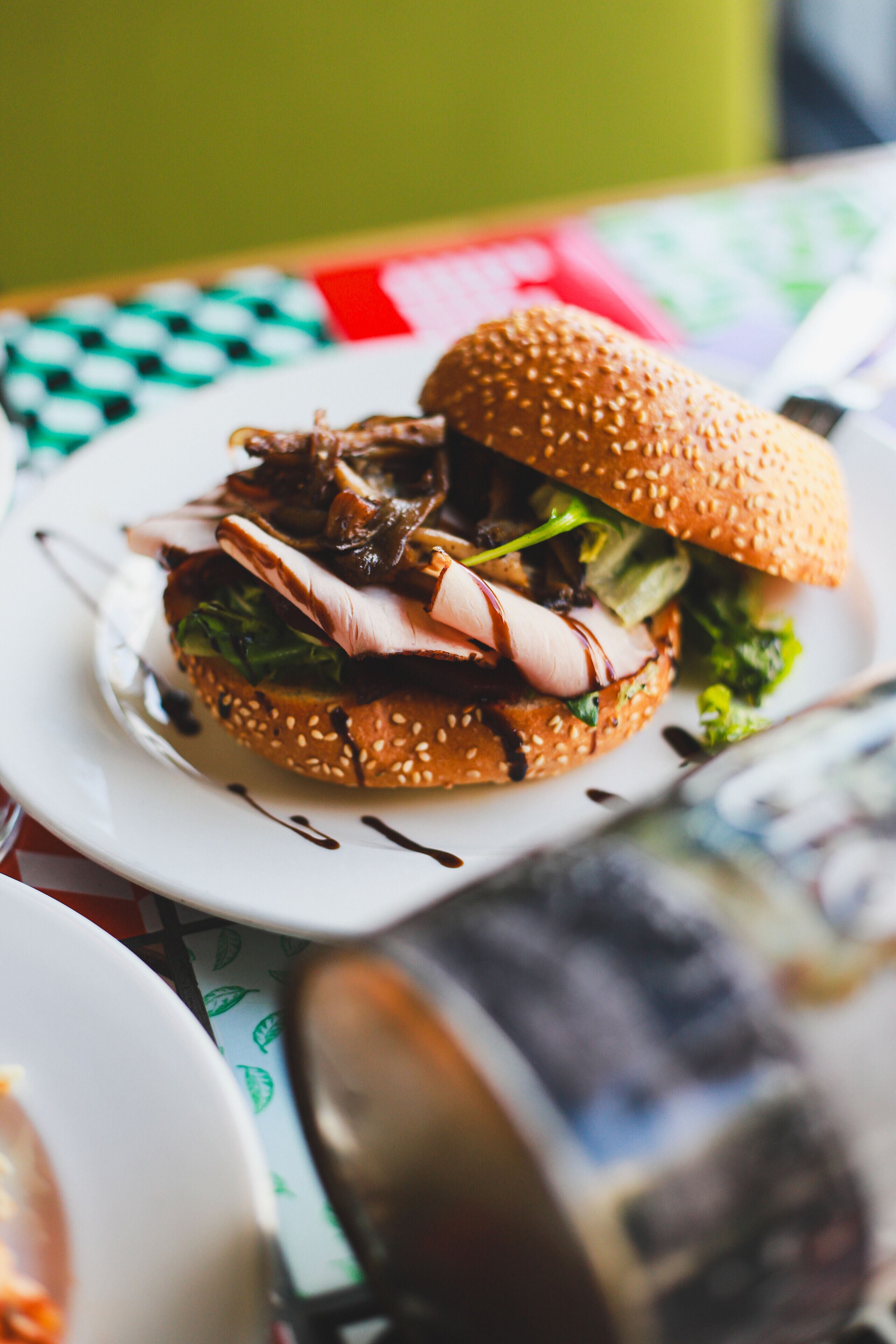 A sandwich on a white plate with a checkered tablecloth.