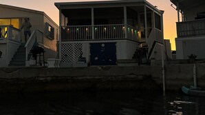 A waterfront building with a covered deck, a blue door, and a staircase leading to the entrance. - Pelican's Roost, Waterfront comfort at Venture Out (Cudjoe Key)