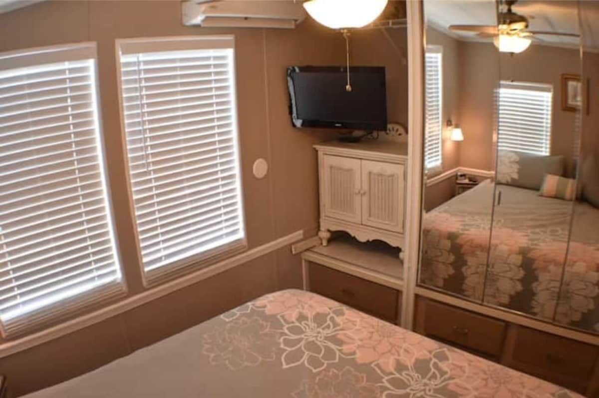 A bedroom with a bed, a television, a wardrobe, and a mirror.