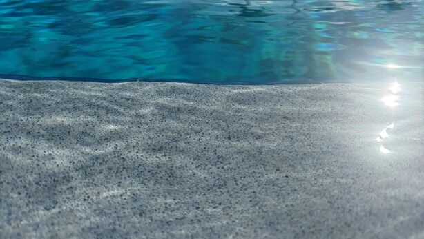 A clear blue pool with a smooth surface, surrounded by a concrete deck and palm trees in the background. - Pelican's Roost, Waterfront comfort at Venture Out (Cudjoe Key)