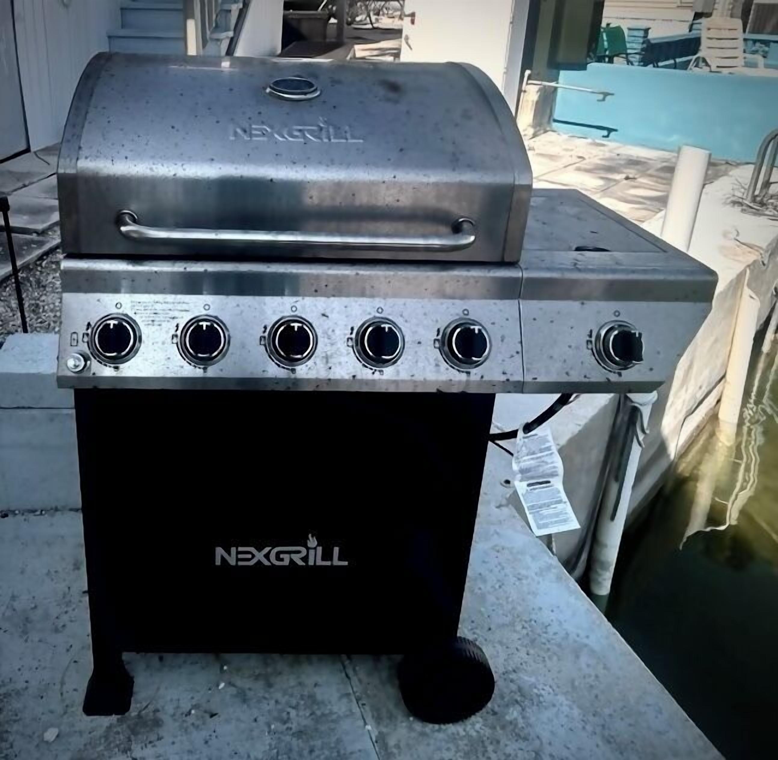 A NEXGRILL barbecue grill with four burners and a lid, placed on a concrete surface outdoors.