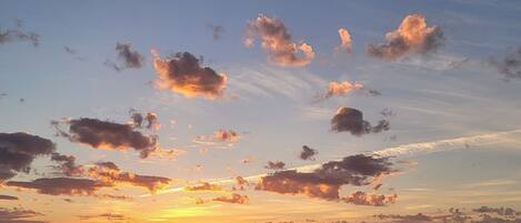 A sunset over a calm sea with scattered clouds.