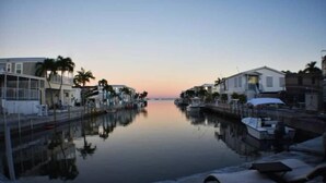 A marina at dusk with calm waters reflecting buildings and palm trees. - Pelican's Roost, Waterfront comfort at Venture Out (Cudjoe Key)