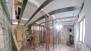 Habitación en construcción con vigas a la vista, materiales de construcción y paredes sin terminar.