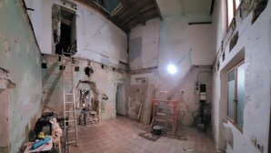 Habitación en renovación con paredes a la vista, una escalera, materiales de construcción y un ventanal visible.