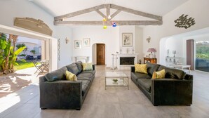 Un salón amplio con dos sofás de cuero negro, una mesa de centro de vidrio y una chimenea.