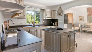 Una cocina moderna con una isla central, armarios blancos y un ventanal que proporciona luz natural.