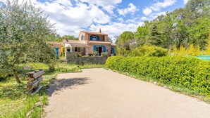 A house with a stone wall and a paved driveway leading to the entrance.
