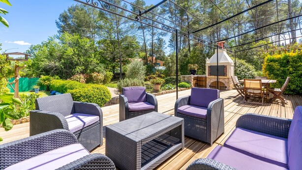 An outdoor patio with wicker furniture and a stone chimney.