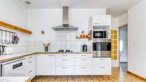 A modern kitchen with white cabinets, a stainless steel range hood, a microwave, and an oven.