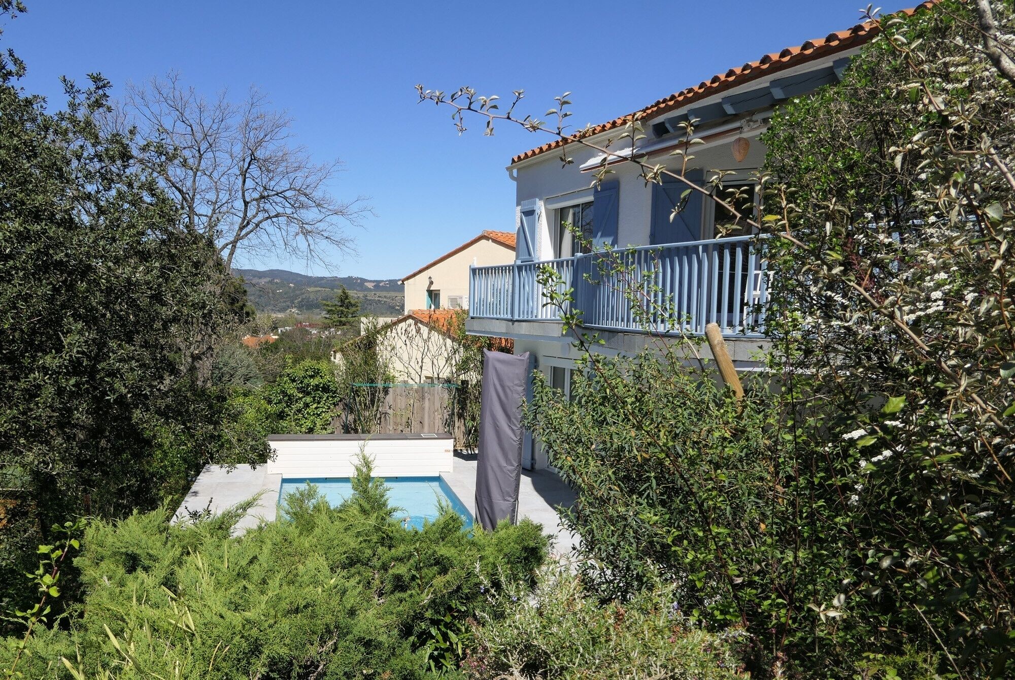 Ein Haus mit Pool, umgeben von dichter Vegetation und Hügeln im Hintergrund.