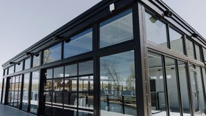 Un bâtiment moderne doté de grandes fenêtres en verre et d’un toit plat.