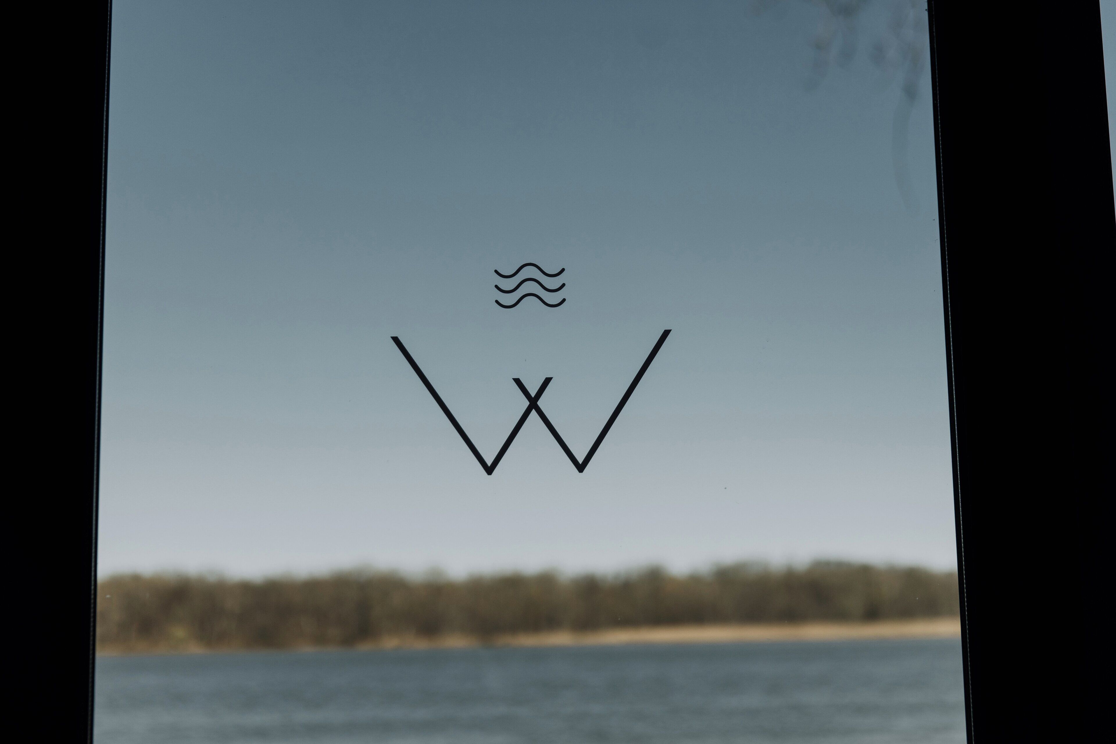 A logo with a wave and a 'W' on a clear sky background.