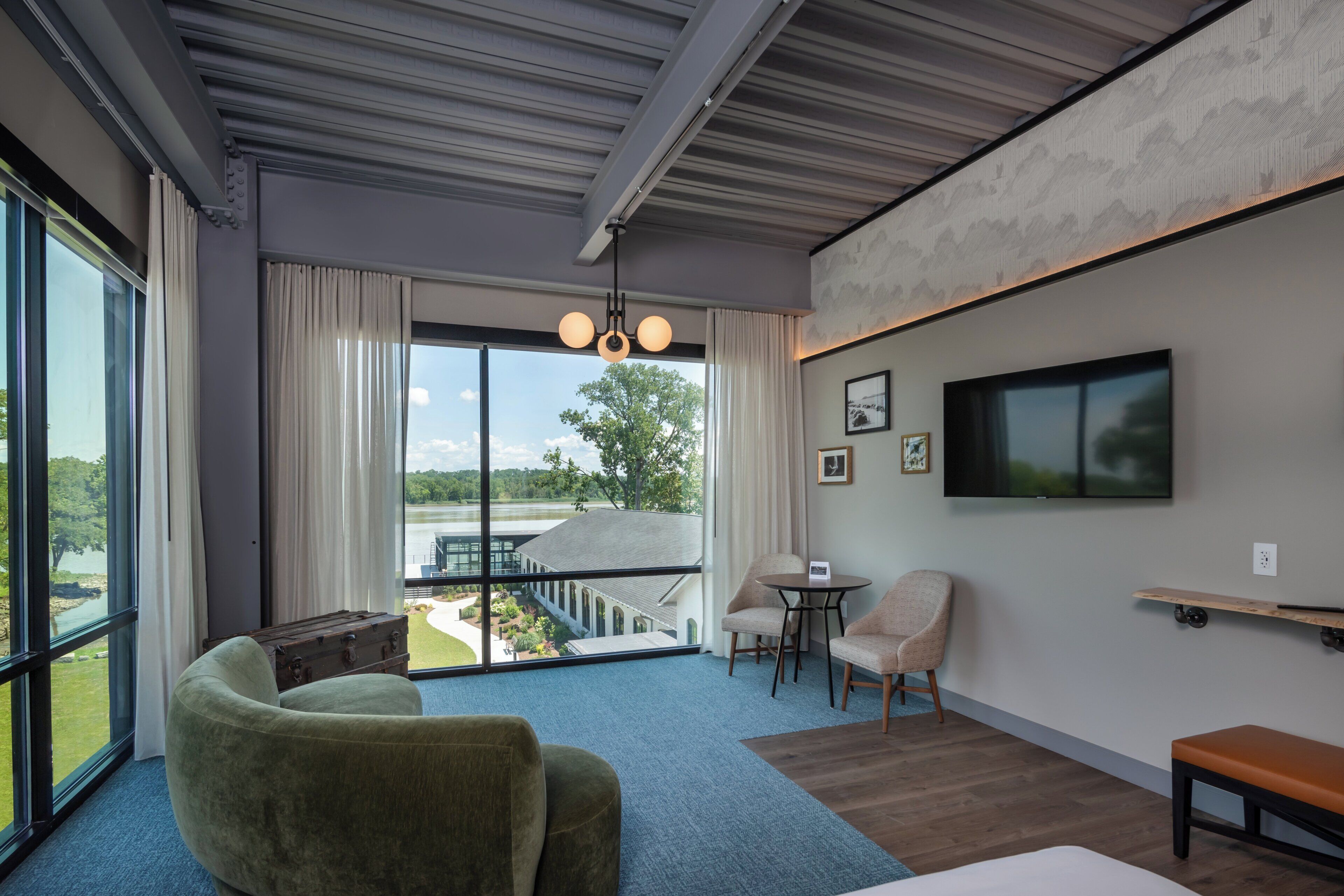 Una habitación de hotel moderna con un ventanal grande, un área de descanso acogedora, un televisor de pantalla plana y una mesita.