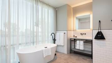 Un baño moderno con una bañera independiente, un tocador con espejo y un perchero para toallas.
