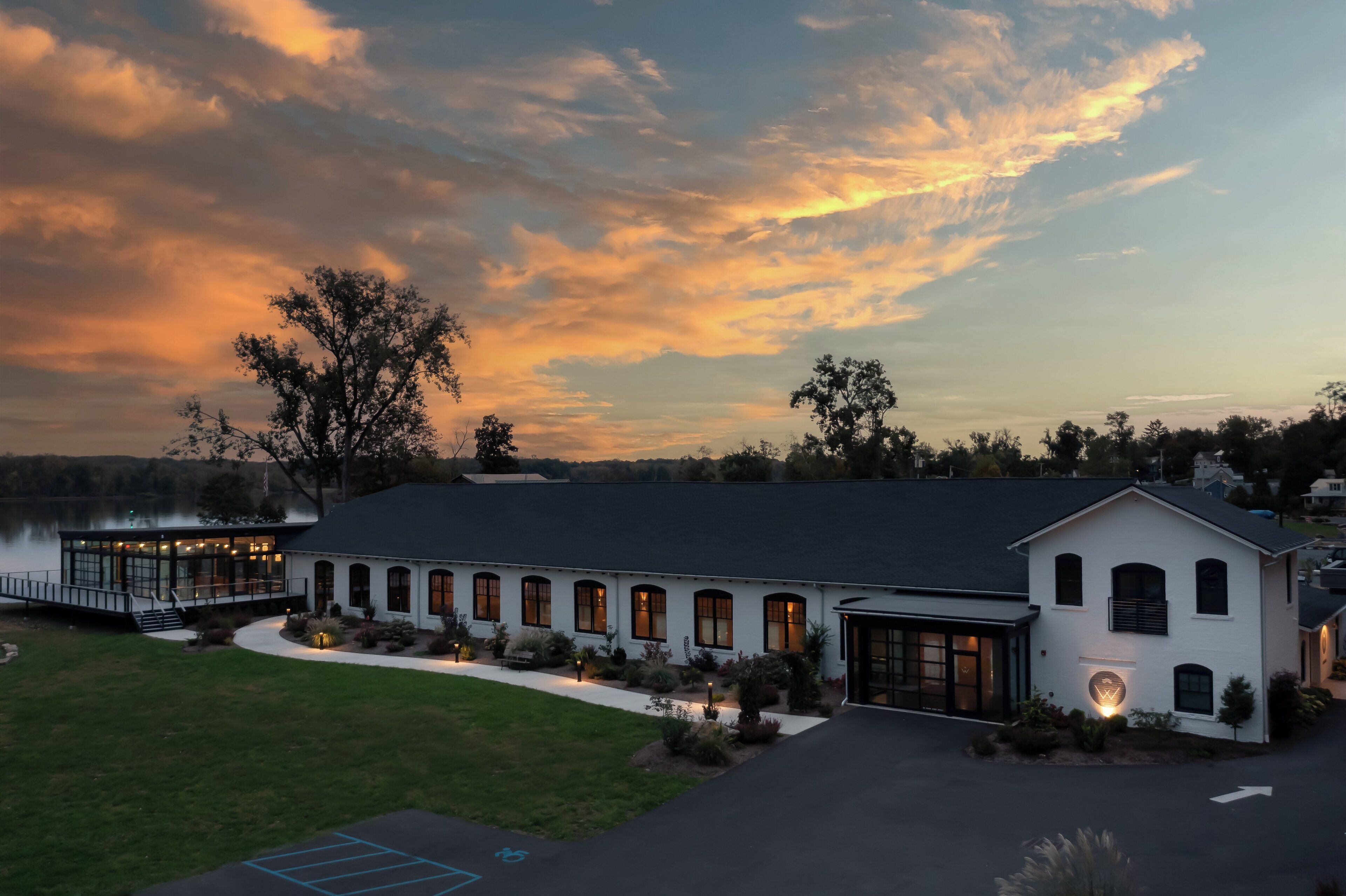 A lakeside hotel with a large building, a covered patio, and a view of the lake.