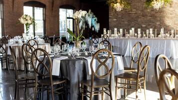A banquet hall with round tables, chairs, and floral centerpieces.