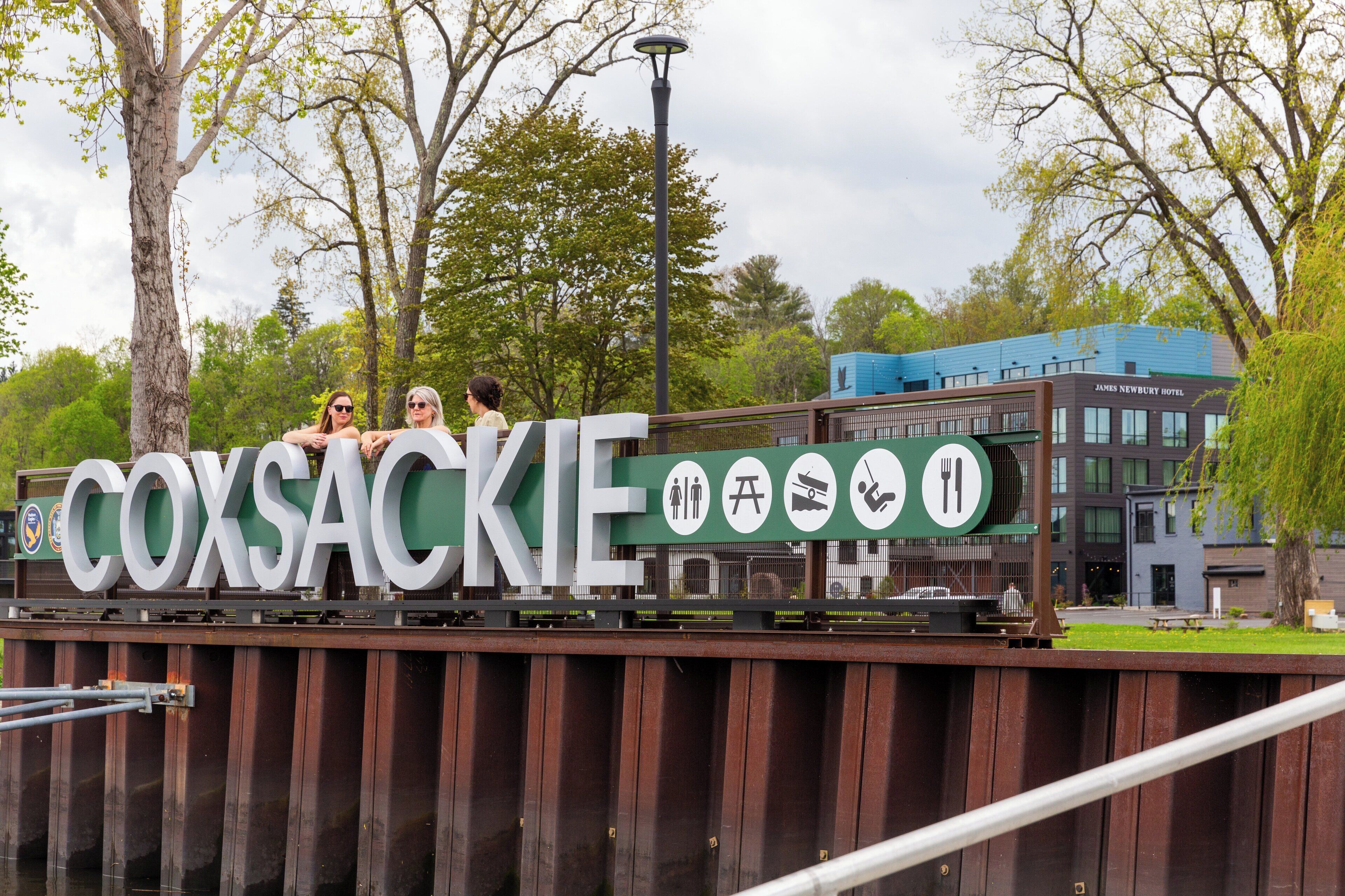 Un panneau indiquant le mot « COXSAKIE » et des symboles représentant les commodités disponibles, comme des toilettes, un restaurant et une piscine.