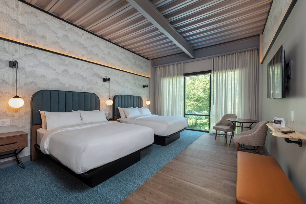 Een moderne hotelkamer met twee bedden, een bureau, een stoel en een televisie.