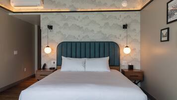 A neatly made bed with a headboard, two bedside tables with lamps, and a wall-mounted air conditioner.