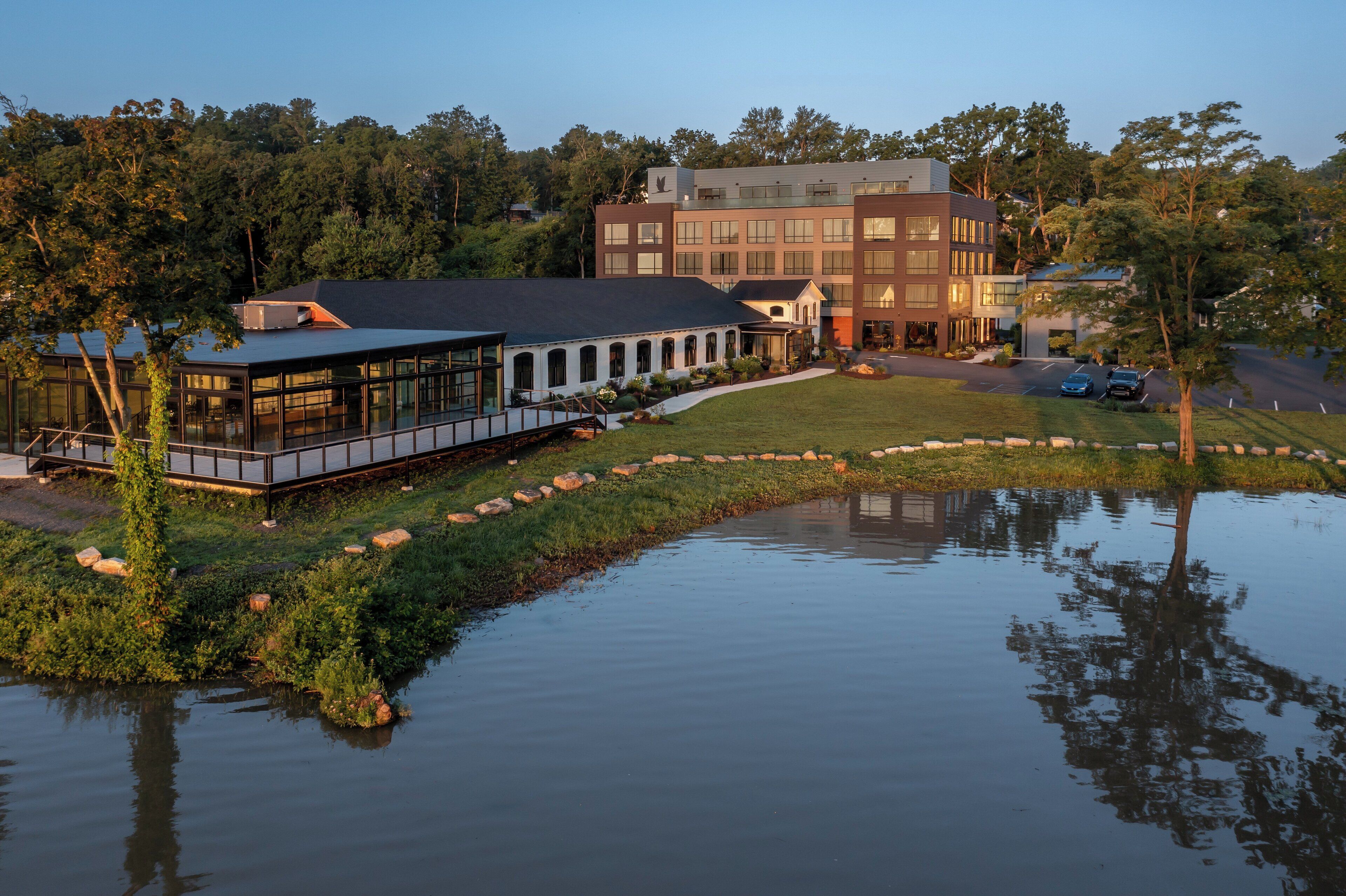 A lakeside building with a glass facade, a covered walkway, and a parking area.