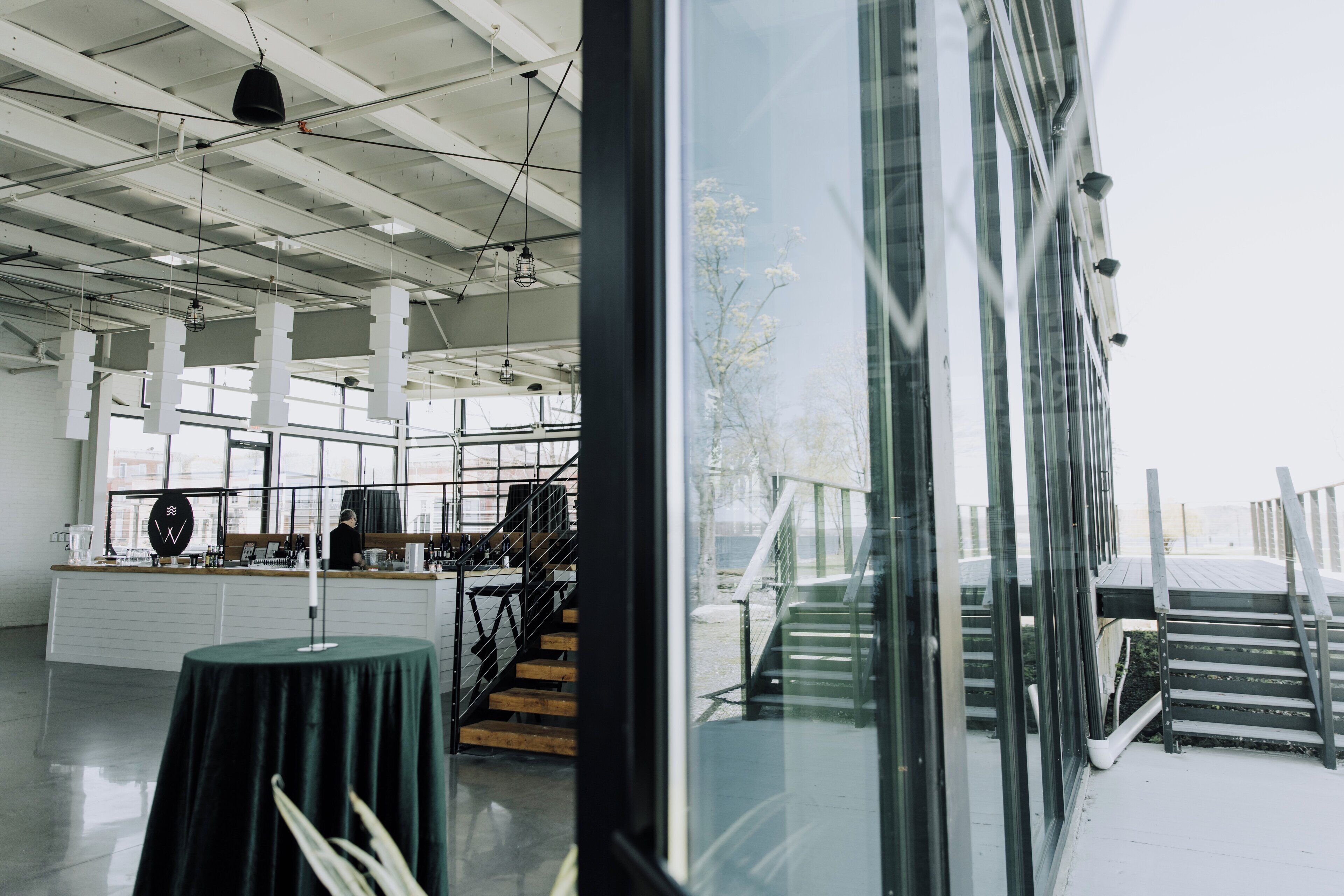An interior space with a reception desk, staircase, and large windows.