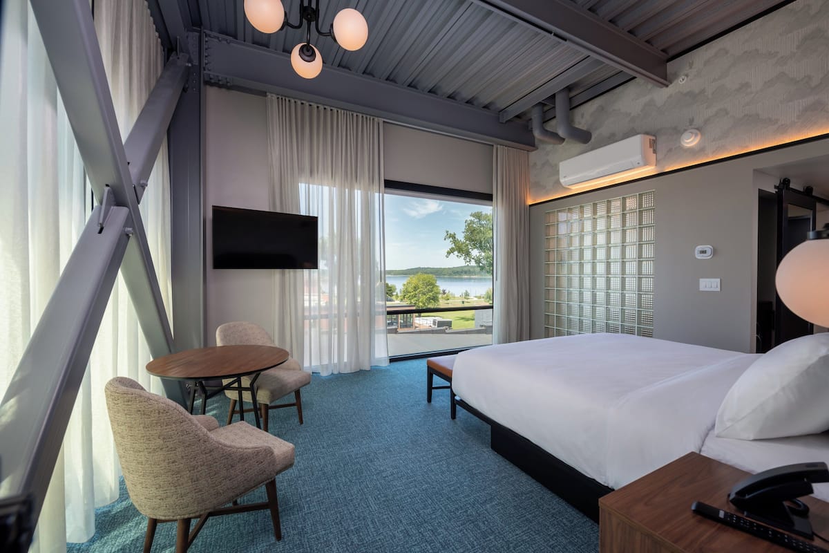 Hotelkamer met een groot bed, een bureau, twee stoelen, een televisie en uitzicht op de omgeving.