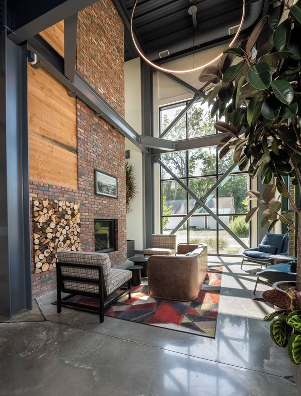 Een modern interieur met een metselwerk open haard, comfortabele zitplaatsen en grote ramen met uitzicht op de omgeving.