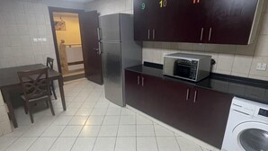 A kitchen with a refrigerator, microwave, and washing machine. There is a dining table and chairs. - Pharaohs Inn Deira Hostel (Dubai)