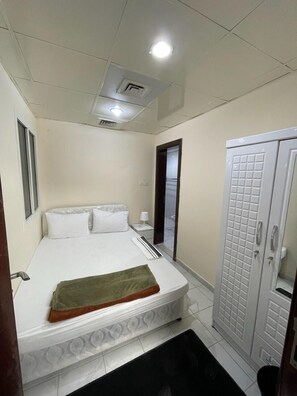 A small, clean room with a bed, a wardrobe, and a mirror. - Pharaohs Inn Deira Hostel (Dubai)