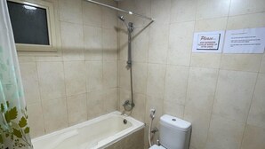 A bathroom with a bathtub, toilet, and bidet. There is a sign on the wall instructing to keep the bathroom clean by wiping up after using. - Pharaohs Inn Deira Hostel (Dubai)