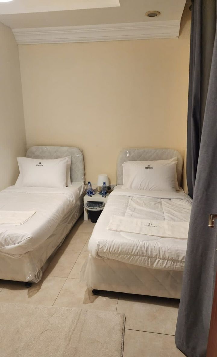 Dos camas individuales en una habitación de hotel con una mesita y un cesto de basura entre ellas.