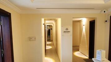 Un couloir d’hôtel avec un comptoir d’accueil, une chaise et un panneau indiquant le nom « Pharaons ».