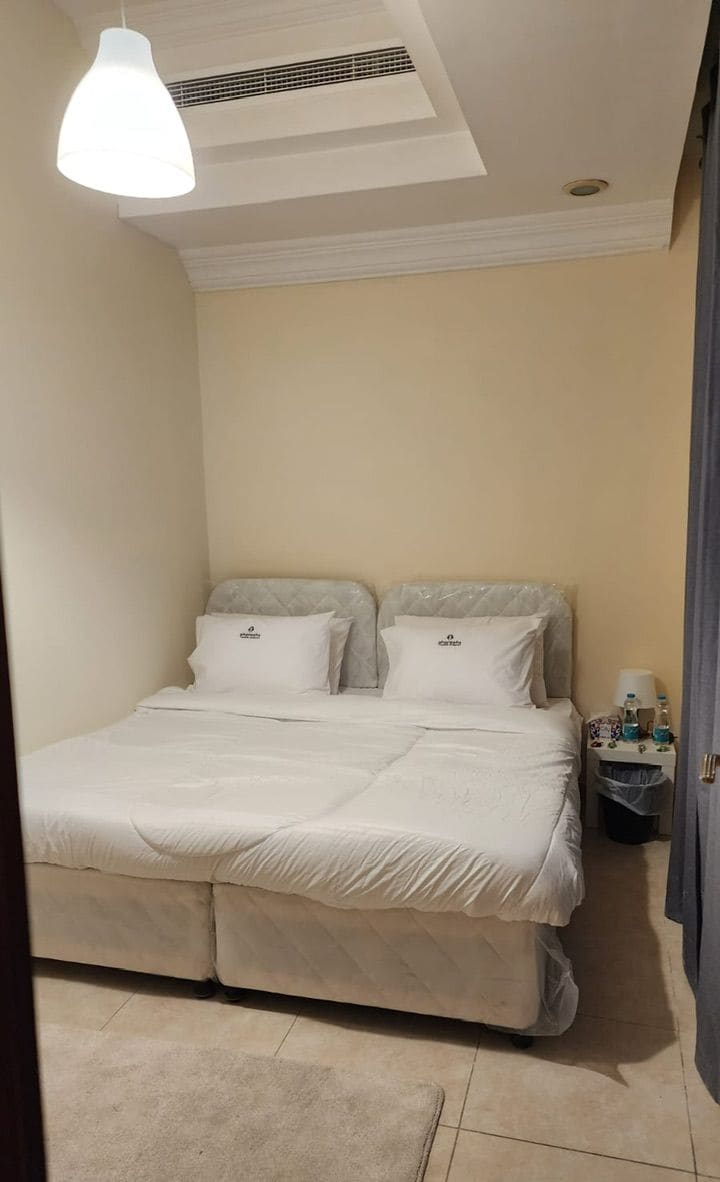 A bedroom with a bed, a nightstand, and a hanging light fixture.