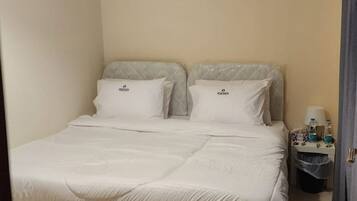 A bedroom with a bed, a nightstand, and a hanging light fixture.