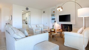 Un salon moderne avec un canapé, des fauteuils, une table basse et un téléviseur fixé au mur.