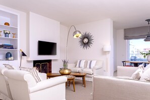 Ein modernes Wohnzimmer mit Flachbildfernseher, Kamin und Essbereich mit Tisch und Stühlen.