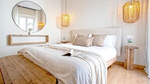 Ein Schlafzimmer mit einem großen Bett, einem runden Spiegel, Nachttischen und einer hölzernen Bank.