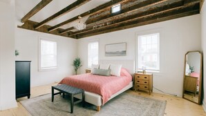A bedroom with a bed, bedside tables, a bench, a dresser, a mirror, and exposed wooden beams. - Newly Renovated, Vintage Inspired, Large 4 BR Home (Mount Joy)