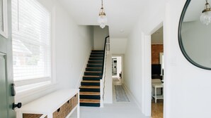 A clean, modern hallway with a staircase, a bench, and a mirror on the wall. - Newly Renovated, Vintage Inspired, Large 4 BR Home (Mount Joy)